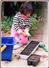 Helping children garden - Girl learning how to plant vegetables